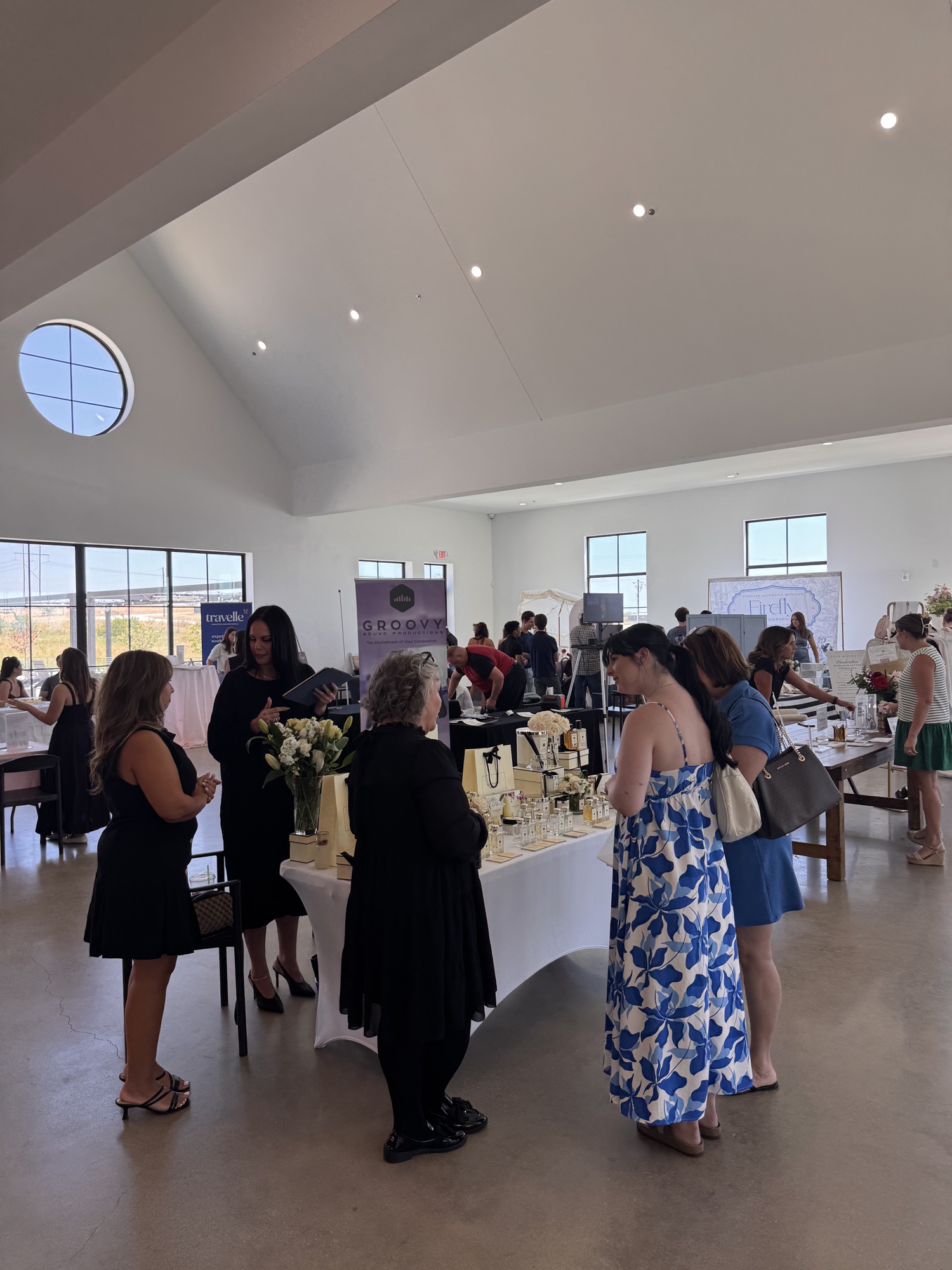 Vendors talking with couples at a Bride Expo show in a bright wedding venue.